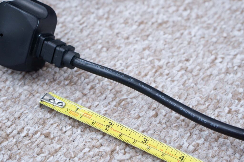 Black flex with moulded plug along side a tape measure. Writing on the flex shows the cable cross-sectional area, 1mm in this case.
